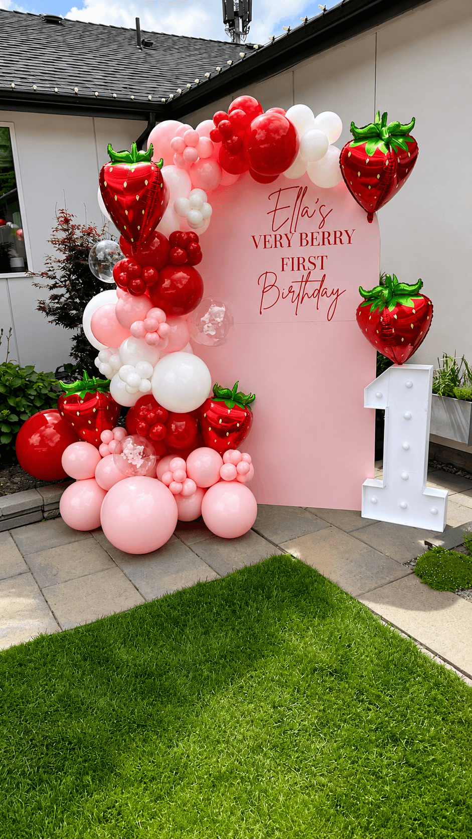 Strawberry-themed balloon garland arch for a first birthday party in Marysville, WA