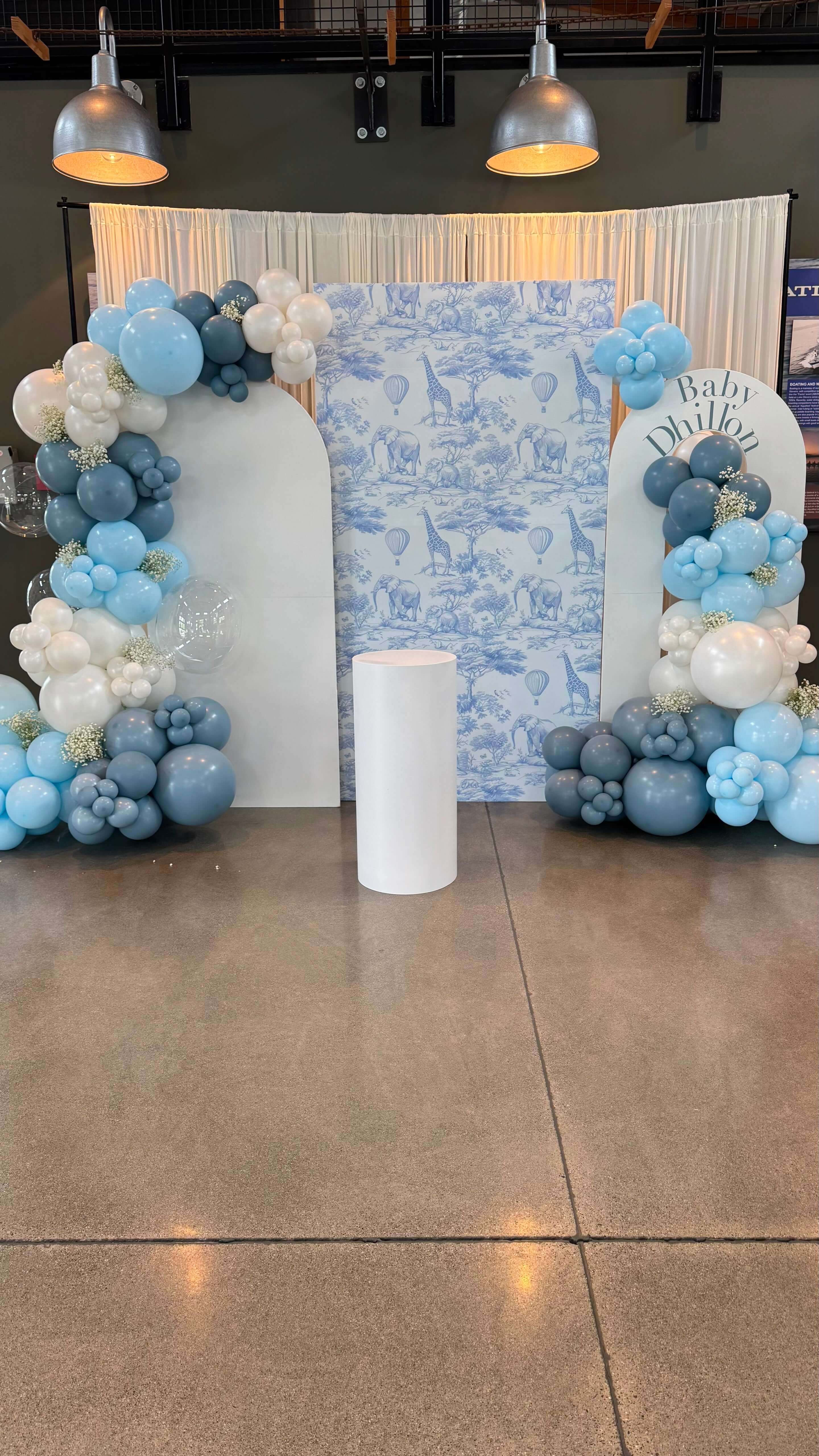 Dusty-blue and white balloon arches with a safari animal toile backdrop for the 'Baby Dhillon' baby shower