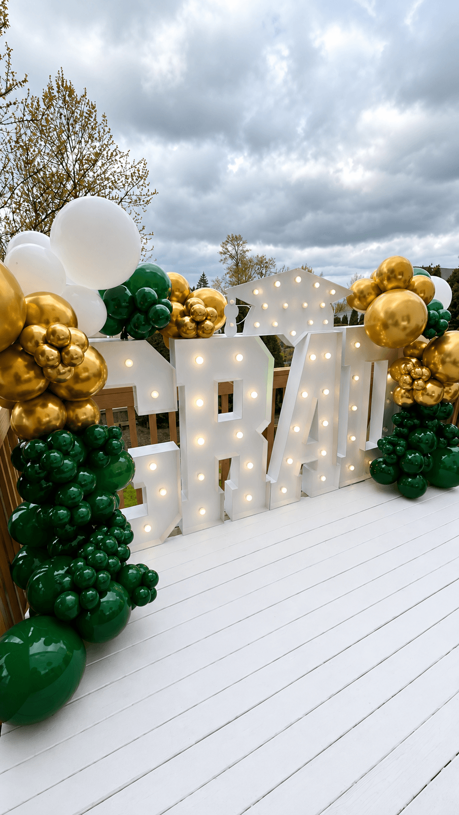 Green and gold LED letters and balloon decor for a graduation celebration